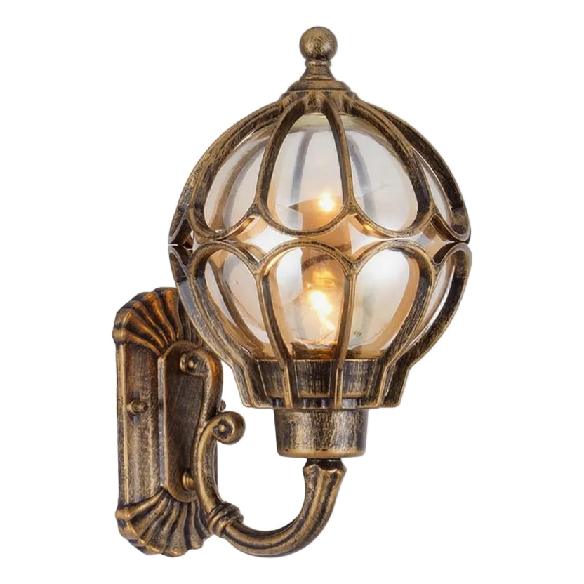 An antique bronze outdoor wall sconce with a clear glass globe shade and a warm glowing light bulb, shown against a plain white background.
