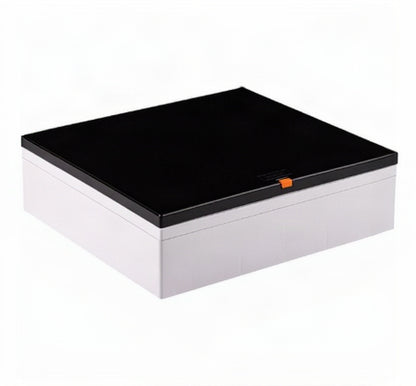 A rectangular storage box with a glossy black lid and a white base, featuring a small orange accent tab on the front of the lid, shown on a plain white background.